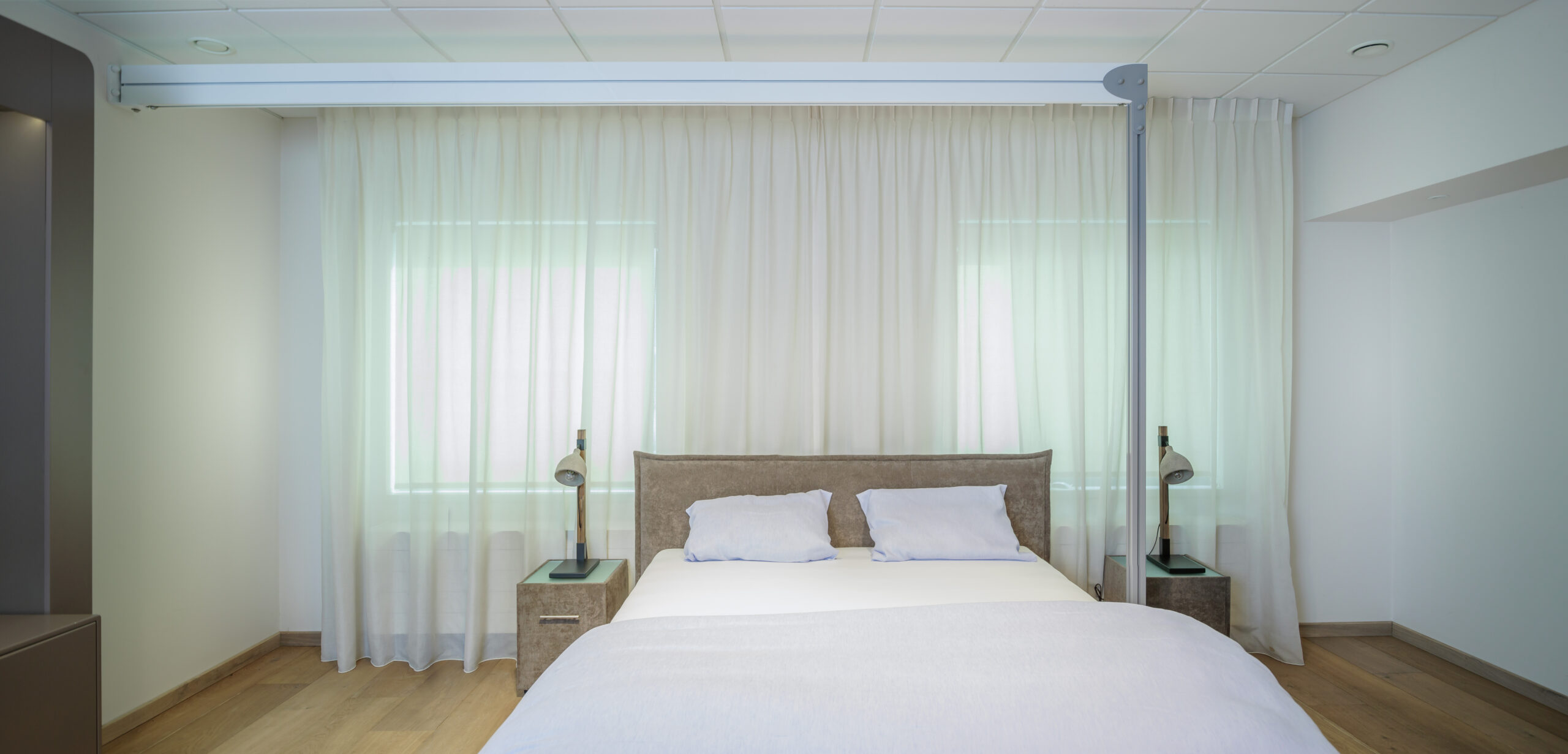 Vrijstaande plafondlift op palen boven een bed in een slaapkamer